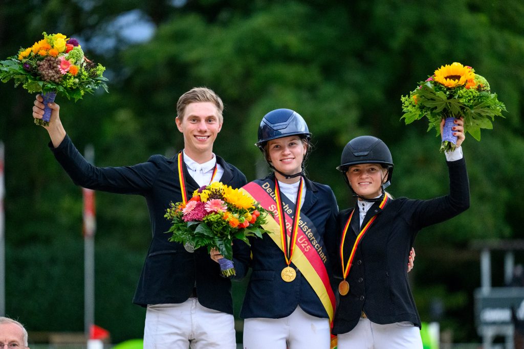 Die glücklichen Medaillengewinner der U25 DM in Riesenbeck 2025: Johanna Beckmann (Gold, Mitte), Hannes Ahlmann (Silber) und Britt Roth (Bronze). Foto: RI/Equitaris